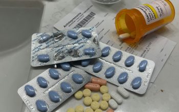 Prescription antidepressant pills in blister packs beside an orange prescription bottle and a glass of water